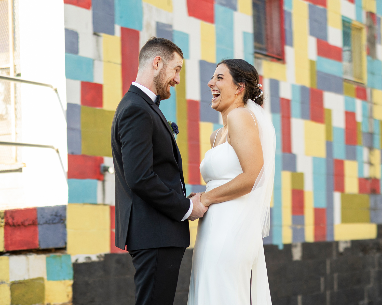 excited newlywed couple laughing under a lovely mural of blocks of color