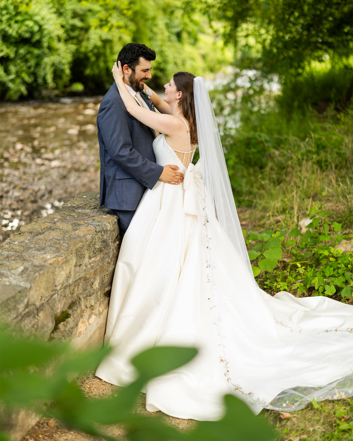 happy newlyweds at a stone wall by the riverside